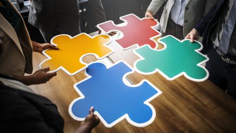 image of employees around a table piecing together a jigsaw puzzle