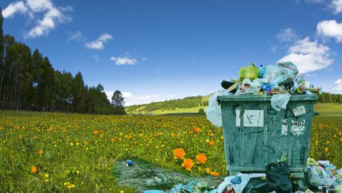 Image of an overfilling trash bin in an open field 