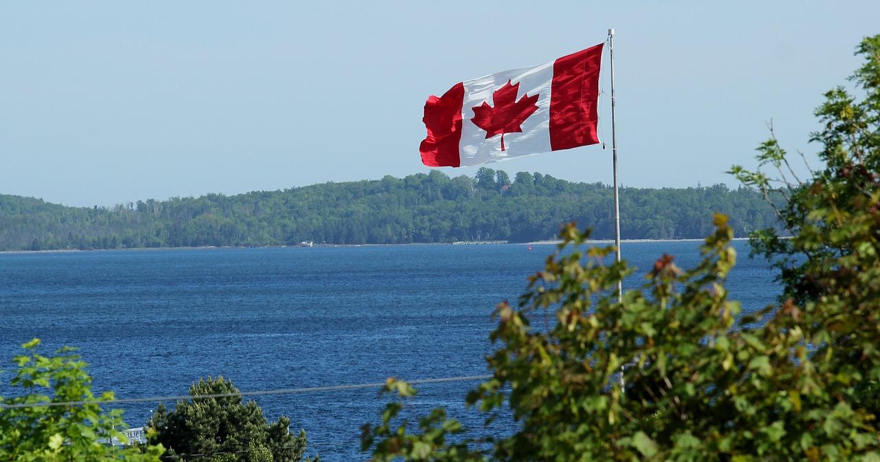 Image of the Canadian flag over a body of water courtesy of Jan Temmel on Pixabay