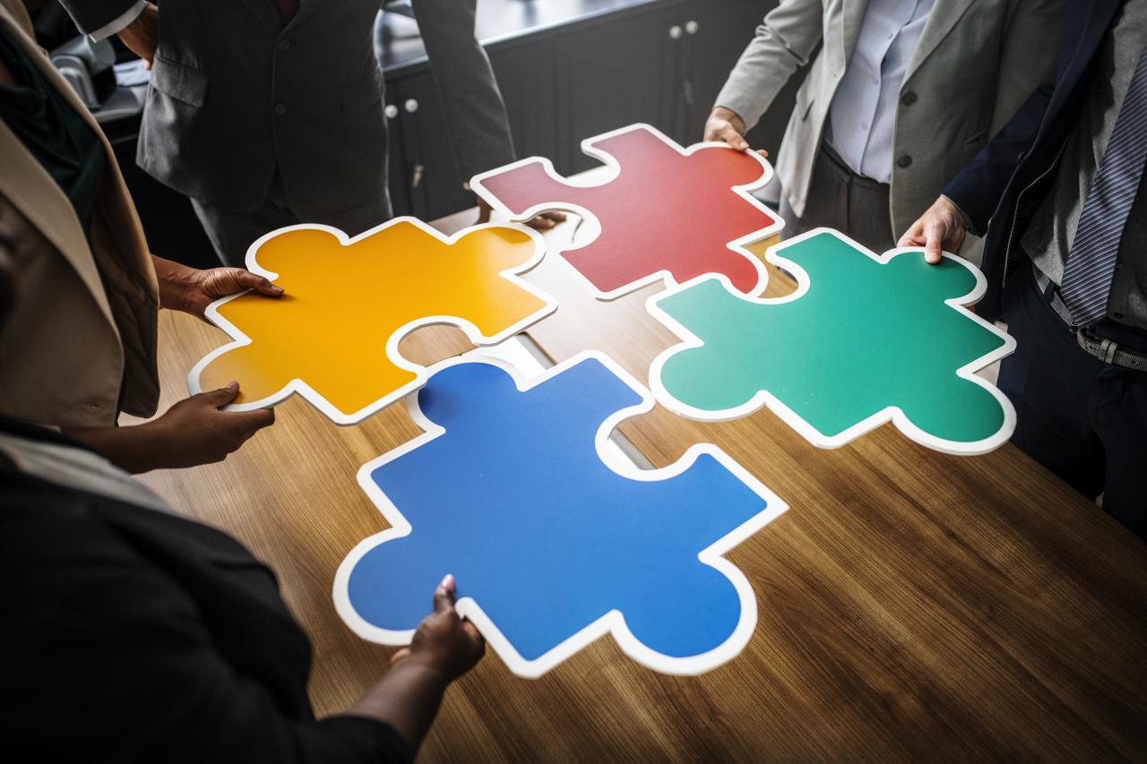 image of employees around a table piecing together a jigsaw puzzle