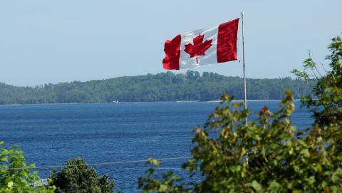 Image of the Canadian flag over a body of water courtesy of Jan Temmel on Pixabay